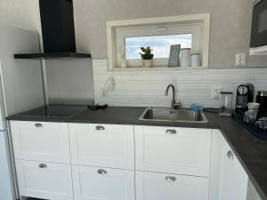 a kitchen with white cabinets and a sink and a window at house with sea view in Varberg +19 photos
