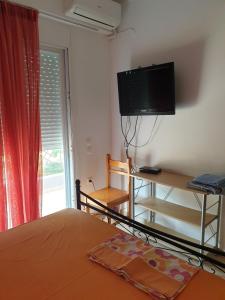 a bedroom with a bed and a flat screen tv at Εξοχικό Σταμάτη in Lóngos