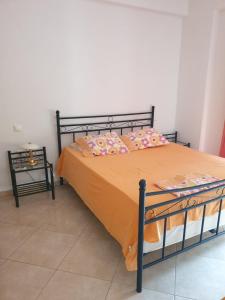 a bed with orange sheets and pillows in a room at Εξοχικό Σταμάτη in Lóngos