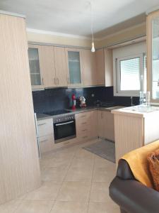 a kitchen with wooden cabinets and a stove top oven at Εξοχικό Σταμάτη in Lóngos