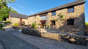 an old stone house with a stone wall at Wagtail Barn in Ipplepen