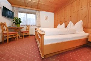 a hotel room with a bed and a table and a television at Rundblick Gästehaus Schruns Tschagguns by Alpenfeder in Schruns