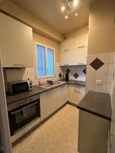 a kitchen with white cabinets and a sink and a microwave at Appartement Millau climatisé in Millau