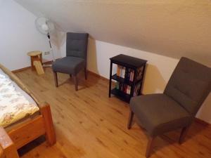 a bedroom with two chairs and a book shelf at Ferienwohnung Hummel in Aurich