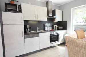 a kitchen with white cabinets and a microwave at Ferienhaus Skanhuus in Klütz +25 photos