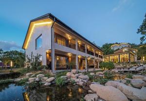 a large house with a pond in front of it at Anji Peiyi Lingfeng Vacation Hotel in Anji
