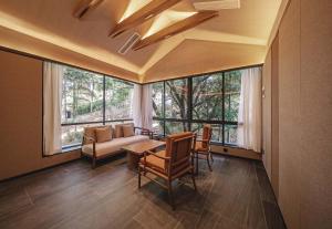 a living room with a couch and a table and windows at Anji Peiyi Lingfeng Vacation Hotel in Anji