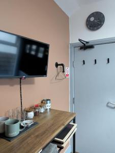 a tv on a wall above a wooden table at R3 - Cozy Small Double - City & Beach Access, WIFI, Free Parking, Bus Stop 50ft From House - Self Catering in Swansea