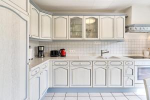a kitchen with white cabinets and a sink at Lund36 in Husum