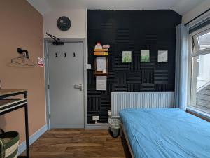 a bedroom with a bed and a black wall at R3 - Cozy Small Double - City & Beach Access, WIFI, Free Parking, Bus Stop 50ft From House - Self Catering in Swansea +18 photos