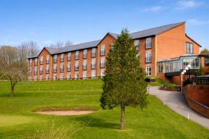 a large brick building with a tree in front of it at Macdonald Hill Valley Hotel, Spa & Golf Resort in Whitchurch