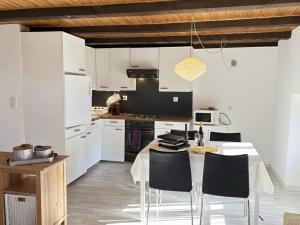 a kitchen with white cabinets and a table with chairs at Le Studio du Rhône in Saint-Léonard