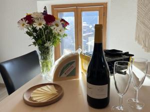 a bottle of wine and a vase of flowers on a table at Le Studio du Rhône in Saint-Léonard