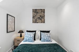 a bedroom with a bed with blue and green pillows at Stylish Roman Bath Abode - The Gatsby in Bath