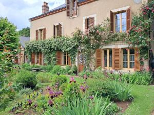 a garden in front of a house with flowers at L'atypique du buisson de la gariole in Aubigny-sur-Nère
