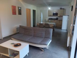 a living room with a couch and a table at Maison individuelle neuve plein pied avec terrasse et jardin clos 15 minutes a pied de la plage arrivé a partir de 15h30 in Quiberville