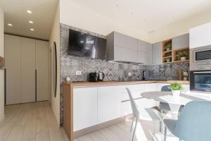 a kitchen with white cabinets and a table with chairs at Residenza Agave in Boario Terme +10 photos