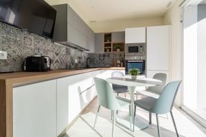 a kitchen with white cabinets and a table and chairs at Residenza Agave in Boario Terme