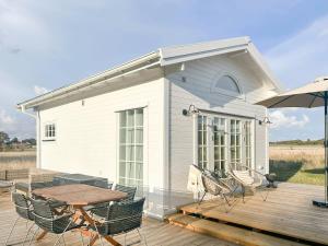 a house with a table and chairs on a deck at Minihus i lantlig miljö nära havet in Smygehamn +8 photos