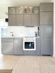 a kitchen with gray cabinets and a white oven at Minihus i lantlig miljö nära havet in Smygehamn