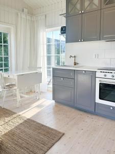 a kitchen with blue cabinets and a sink and a table at Minihus i lantlig miljö nära havet in Smygehamn