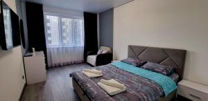 a bedroom with a bed with a chair and a window at Панорама Апарт готель in Ternopil