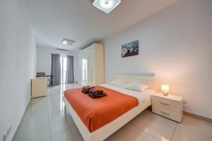 a bedroom with a large bed with an orange blanket at Central, spacious apartment with Sea Views in St. Paul's Bay