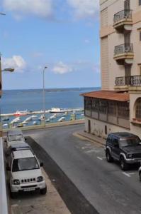 a street with cars parked next to a building at Central, spacious apartment with Sea Views in St. Paul's Bay