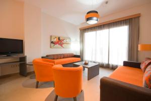 ein Wohnzimmer mit orangefarbenen Stühlen und einem Flachbild-TV in der Unterkunft Alcocebre Suites Hotel in Alcossebre