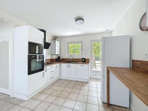 a kitchen with white cabinets and a tile floor at Cozy Alclau in Mimizan