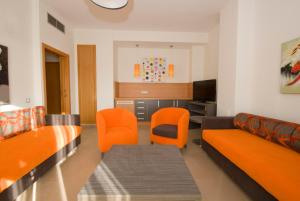 sala de estar con sillas de color naranja y sofá en Alcocebre Suites Hotel, en Alcossebre