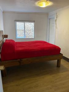 a bedroom with a red bed with a window at Selva Hospedaje in Valparaíso