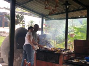 a man and a woman preparing food on a grill at Posada El Remolino in Anolaima