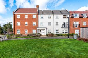 a large brick building with a green yard at Wokingham Stylish Two Bedroom Apartment in Wokingham