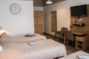 um quarto de hotel com duas camas e uma secretária e uma televisão em Rooms Rebolj em Osijek