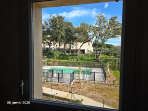 a view of a swimming pool from a window at Spacieux appartement dans résidence avec piscine in Bormes-les-Mimosas