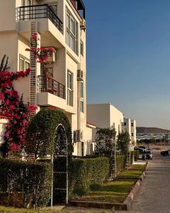 a tall white building with bushes and flowers next to a street at Jasmine in Sharm El Sheikh