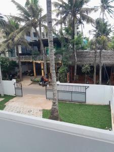 a building with palm trees in front of a park at Hiri Dudes Villa in Dickwella