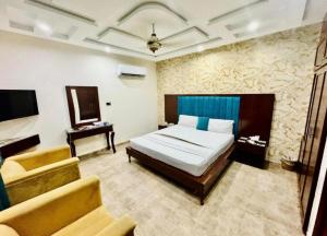 a bedroom with a bed and a couch and a television at Hotel DE Smart Multan in Multan