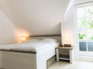 a bedroom with a white bed and a window at Ferienhaus Sonnenblick in Timmendorfer Strand +16 photos