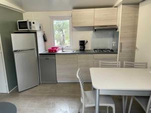 a kitchen with a table and a white refrigerator at Bungalow le Sartène in Lumio