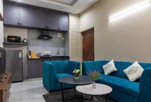a living room with a blue couch and a table at Buteak Suites BTM Layout in Bangalore +9 photos