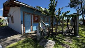 a small house with a palm tree next to it at Quartos Beira Mar ARROIO TEIXEIRA in Capão da Canoa