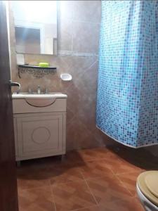 a bathroom with a sink and a blue shower curtain at cabaña huguito y vane in Tinogasta