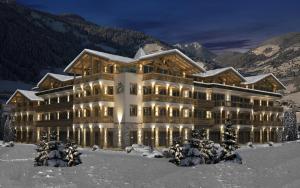 ein großes Gebäude im Schnee in der Nacht in der Unterkunft Residenz Drachenstein Wildschönau in Niederau