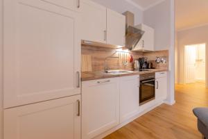 a kitchen with white cabinets and a sink at Villa Odin, Muschelsucher - Bade- & Saunawelt täglich inklusive in Ostseebad Sellin +18 photos