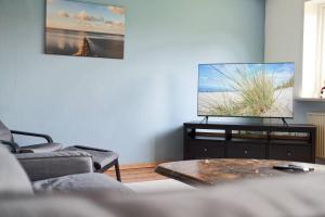 a living room with a couch and a tv on a wall at Wietblick in Ockholm