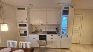 a kitchen with white cabinets and a refrigerator at Lillstugan i Rasbo in Uppsala