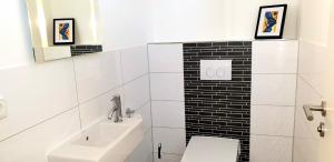 a white bathroom with a toilet and a sink at Reethaus "Alinde" in Zierow