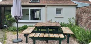 a picnic table and an umbrella in front of a house at Le Jardinet in Pont-Sainte-Maxence